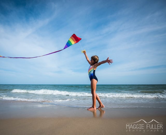 Little girl playing with a kite on the beach