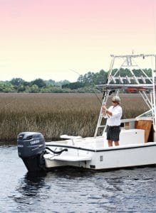 Man Fishing on a boat with the sun setting behind him.
