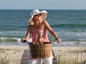 Girl riding bike on beach with dog