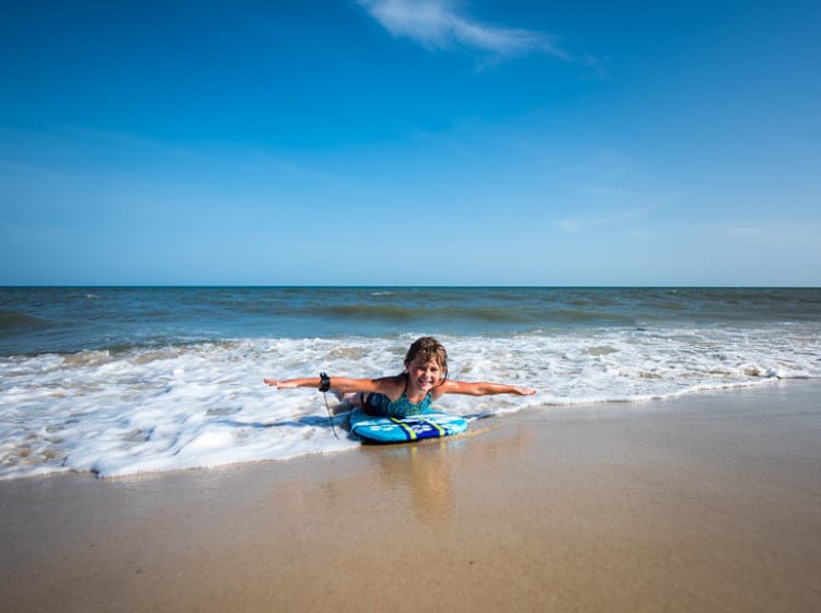 Little girl skim boarding on the beach