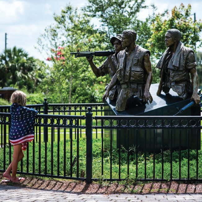 Young girl looking at 3 man statue