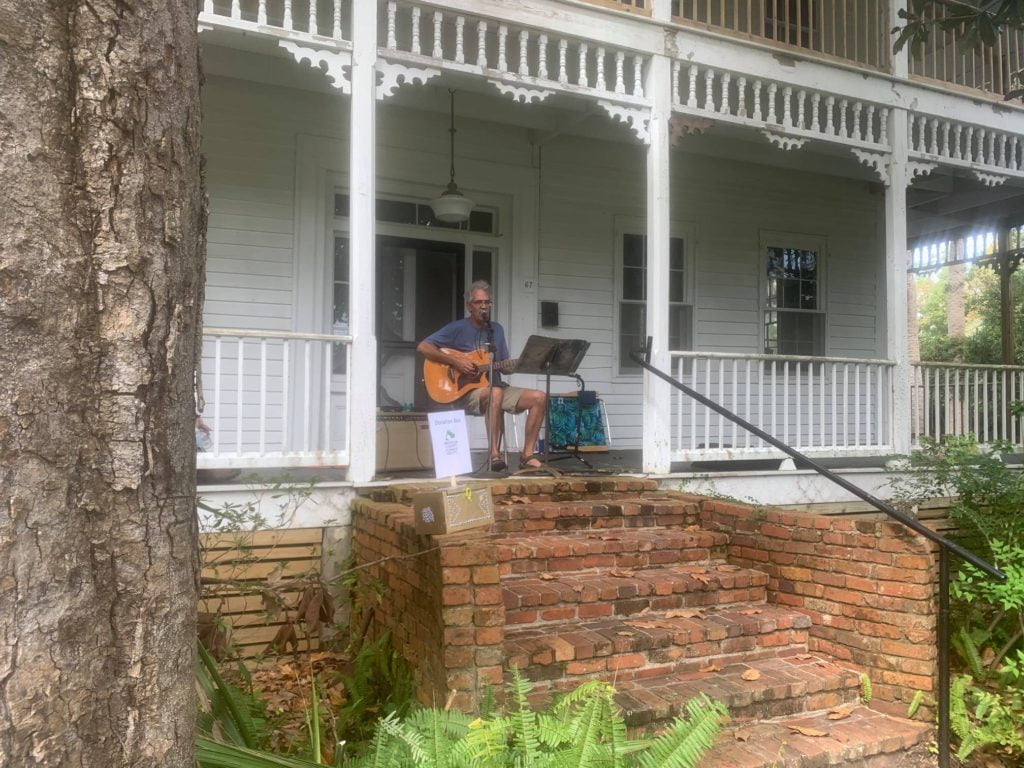 David Lloyd playing guitar and singing on a porch at Porch Fest in Apalachicola, FL.