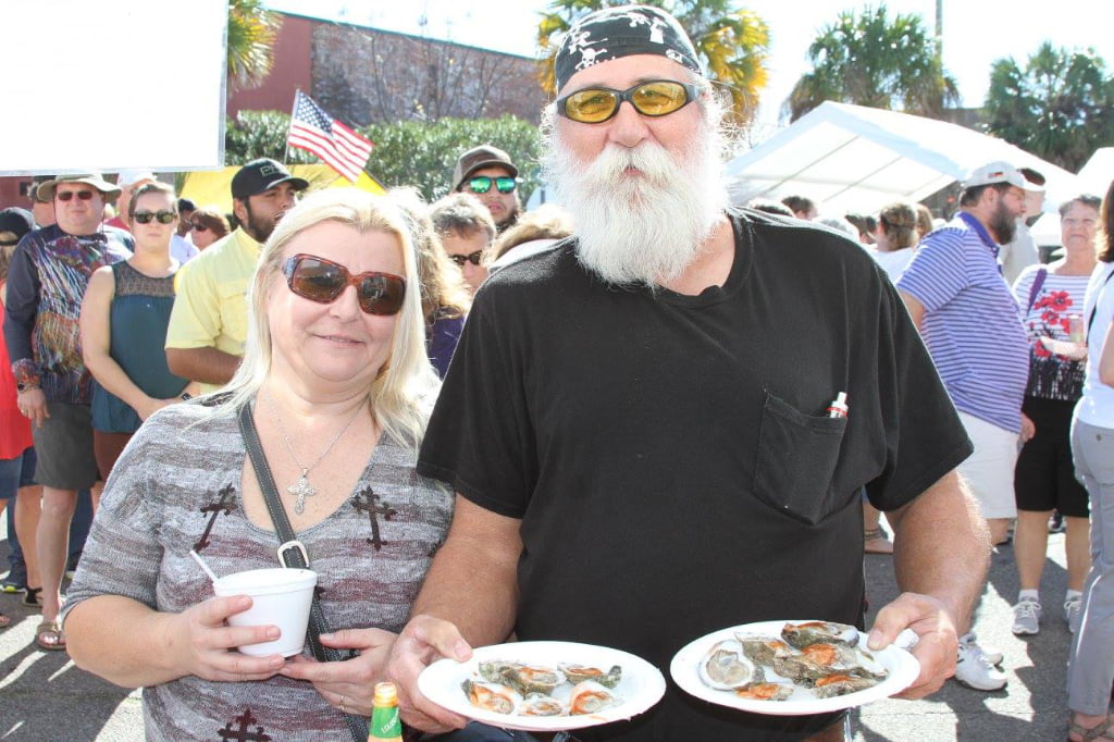 Couple holding beer and plate of oysters