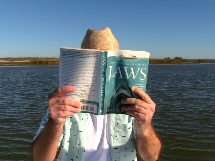 Man in straw hat holding book named JAWS